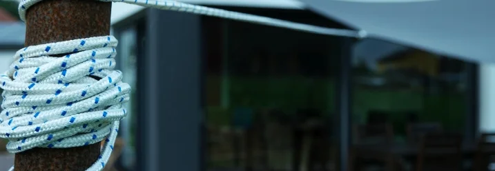 Ein weißes Seil umwickelt einen rostigen Metallpfosten.